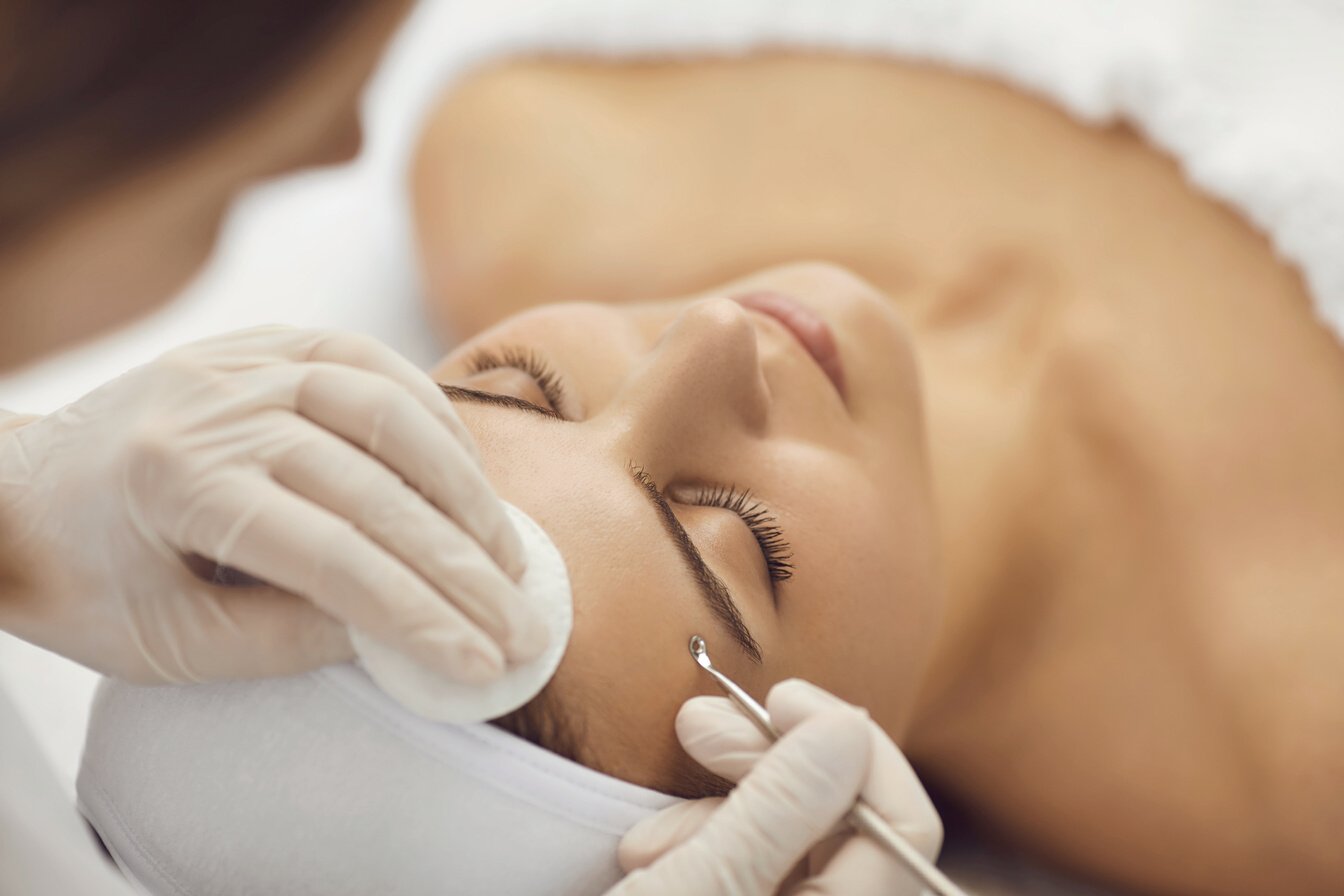 Cosmetologist Making Skin Cleaning for Young Patient Woman in Beauty Salon